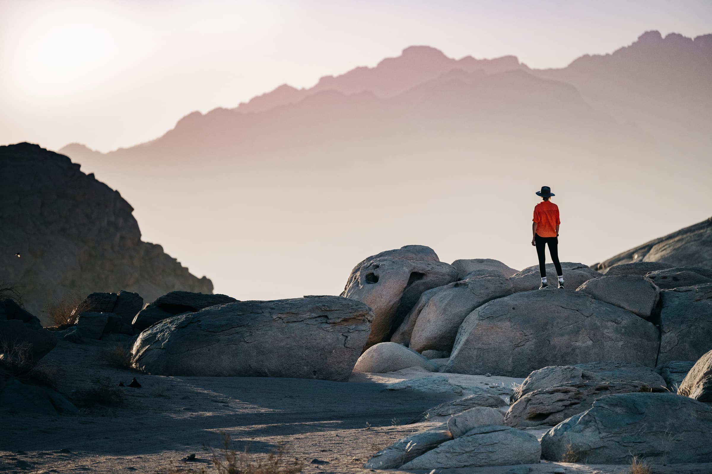 Traveler standing on rock overlooking vast desert landscape